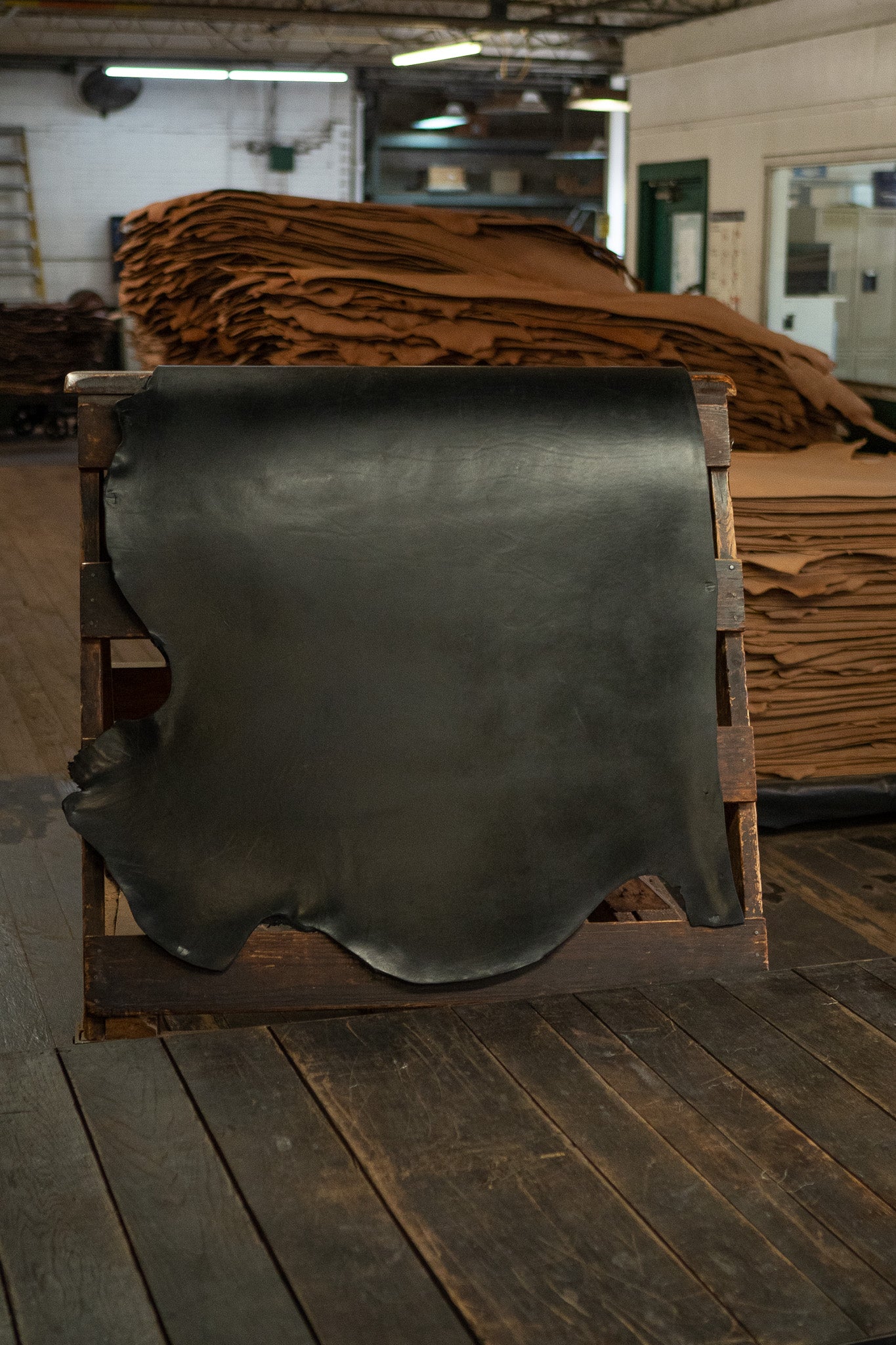 Black English Bridle Leather from Hermann Oak Leather Co displayed on a wooden rack