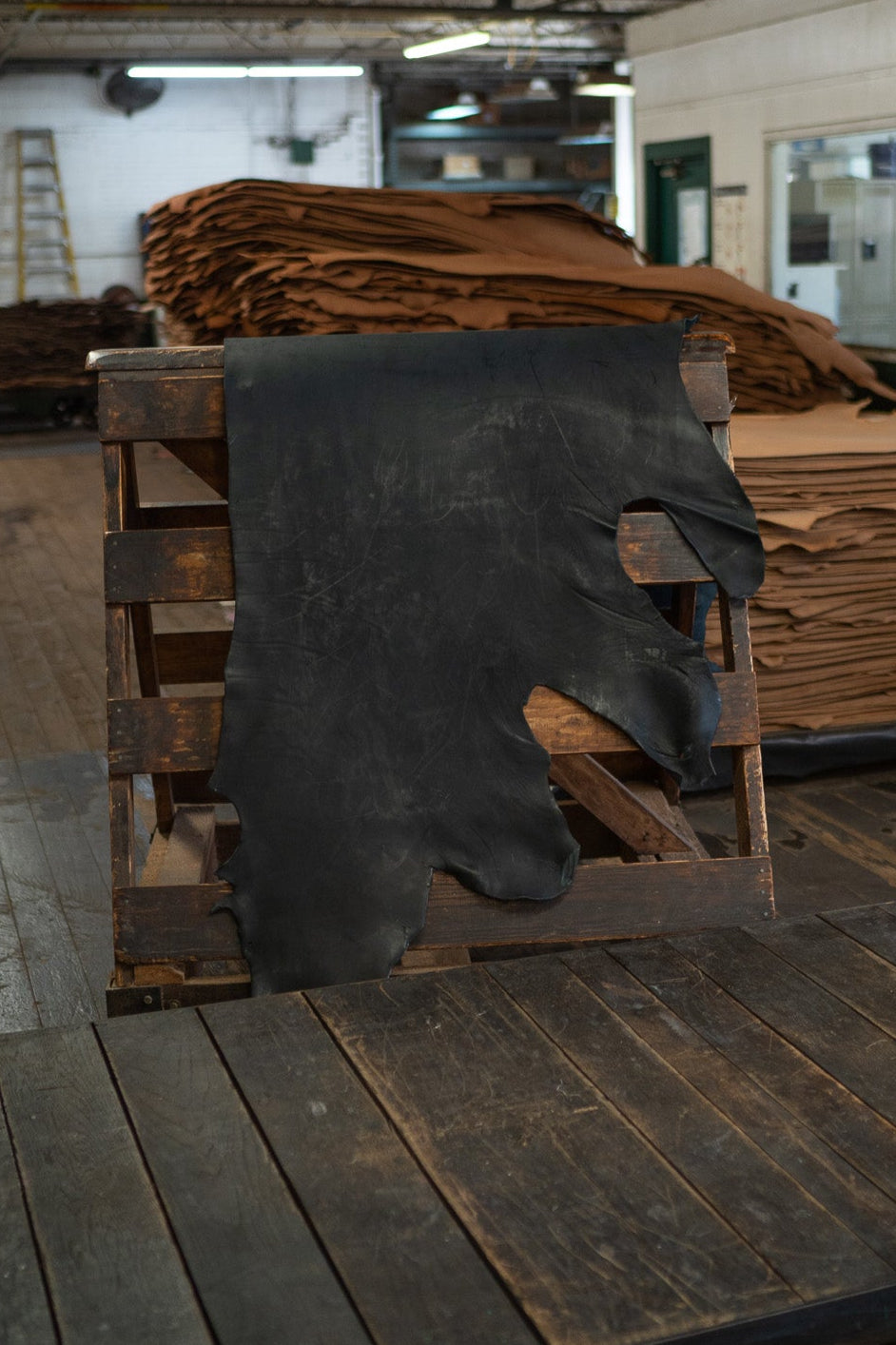 Black Skirting Leather from Hermann Oak Leather Co displayed on a wooden rack