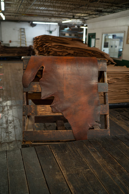 Chestnut Harness Leather from Hermann Oak Leather Co displayed on a wooden rack