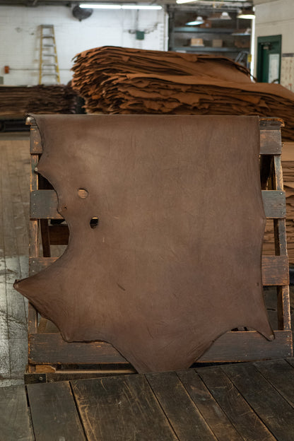 Dark Chocolate Expedition Leather from Hermann Oak Leather Co displayed on a wooden rack