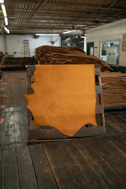 London Tan Heritage Leather from Hermann Oak Leather Co displayed on a wooden rack