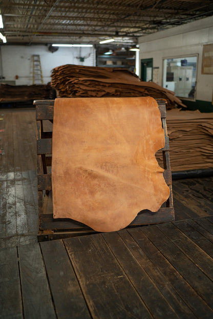 Natural Harness Leather from Hermann Oak Leather Co displayed on a wooden rack