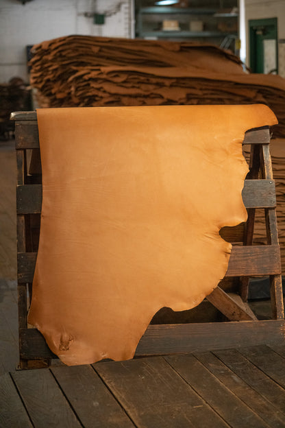 Natural Latigo Leather from Hermann Oak Leather Co displayed on a wooden rack