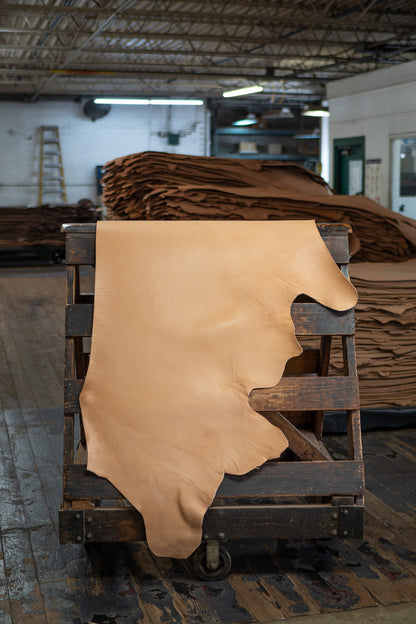 Natural Skirting Leather from Hermann Oak Leather Co displayed on a wooden rack