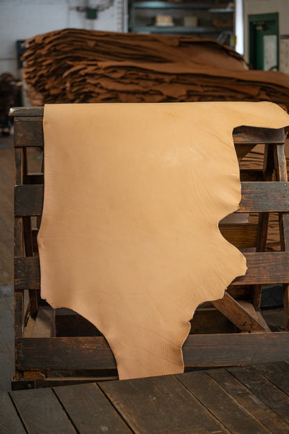 Natural Tooling Leather from Hermann Oak Leather Co displayed on a wooden rack